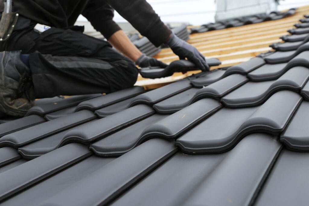 image of man working on black roof tiles